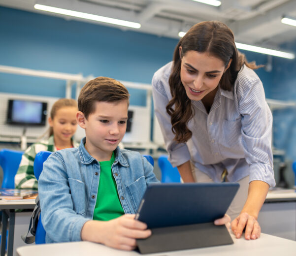 Woman looking into tablet of student boy